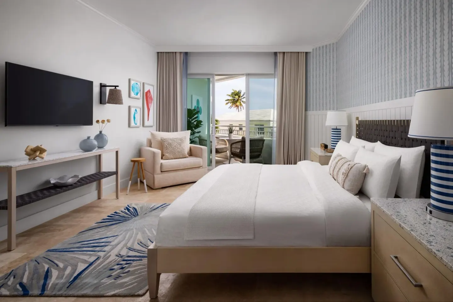 Guest room at Sandals Royal Bahamian with a king bed, TV, armchair, and balcony doors.