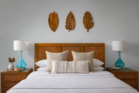 A king bed with cane headboard and turquoise lamps in a guest room at Sandals Royal Bahamian.