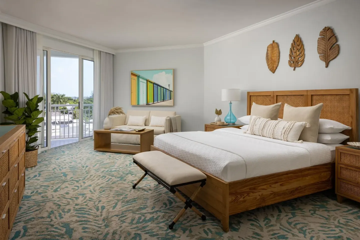 A king bed, sitting area, and balcony doors in a guest room at Sandals Royal Bahamian.