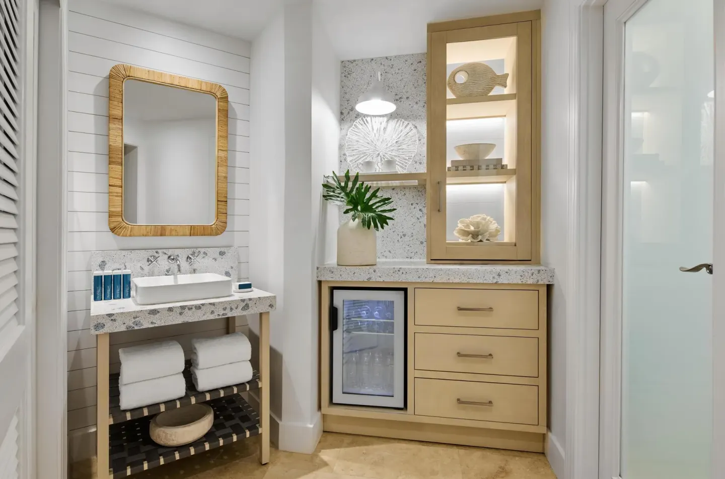 Guest room vanity with sink, towels, and stocked mini fridge at Sandals Royal Bahamian.