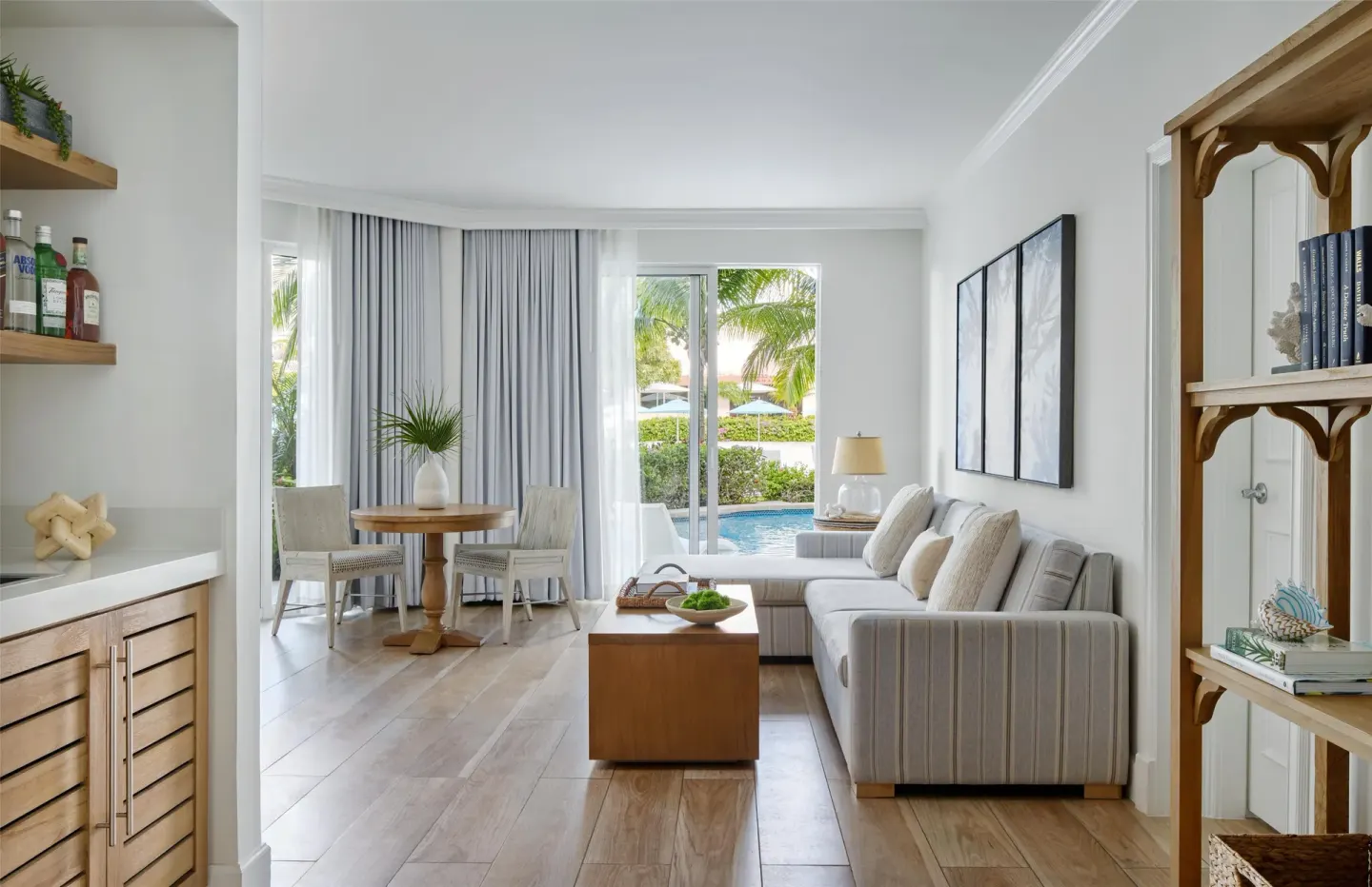 Guest suite living area with sofa, dining table, and pool-facing patio at Sandals Royal Bahamian.