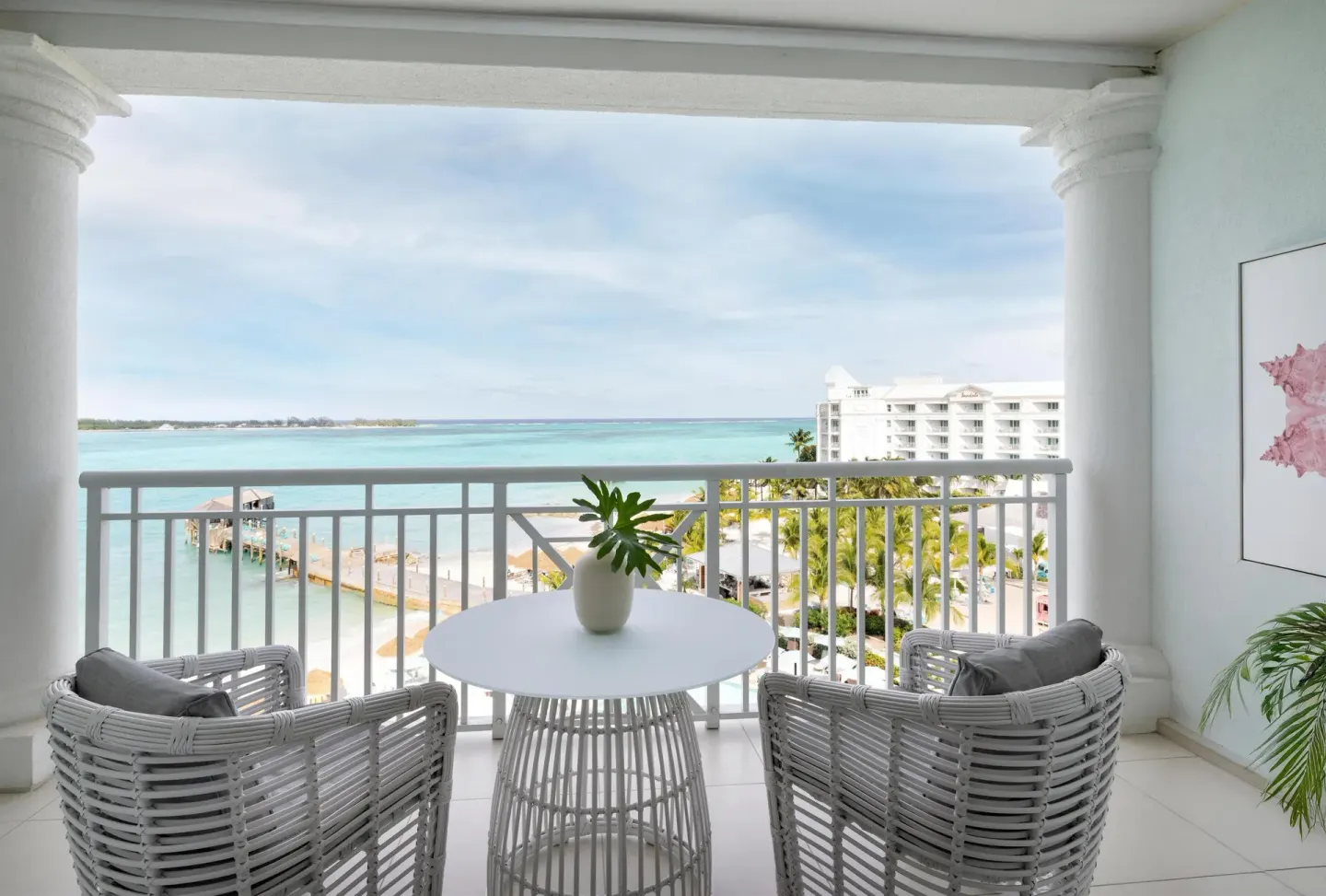 High balcony with table, chairs, beach, pier, and ocean at Sandals Royal Bahamian.