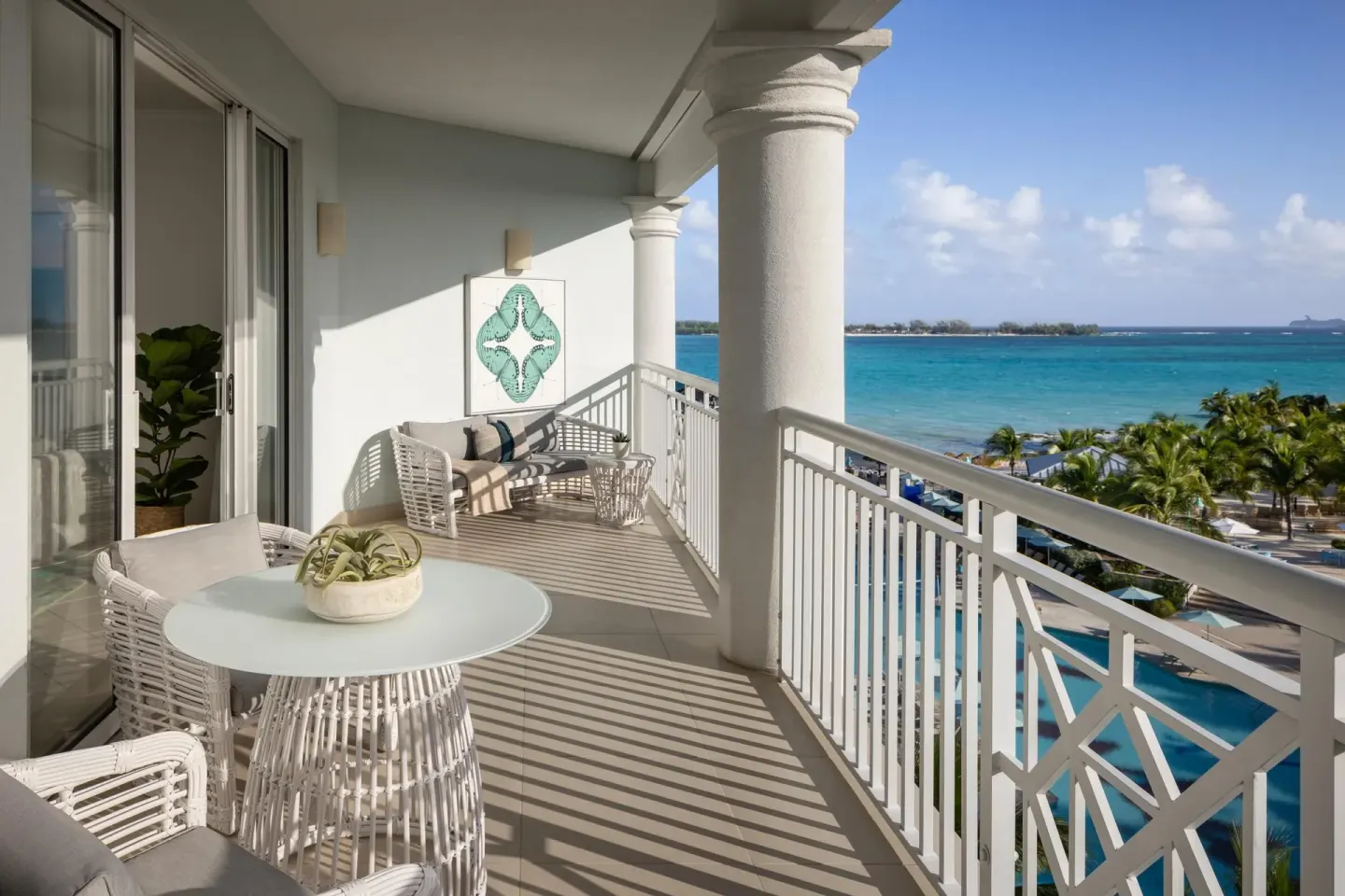 A furnished ocean-view balcony with white railings at Sandals Royal Bahamian.