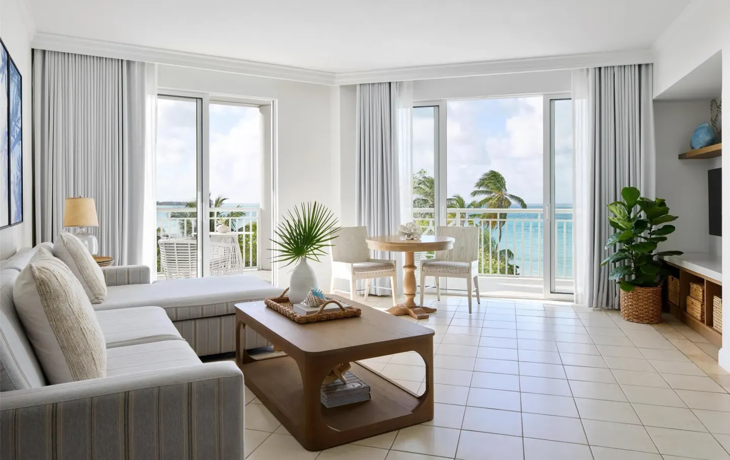Ocean-view living room with sofa, dining table, and balcony doors at Sandals Royal Bahamian.