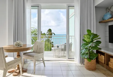 Guest sitting area with balcony and ocean view at Sandals Royal Bahamian.
