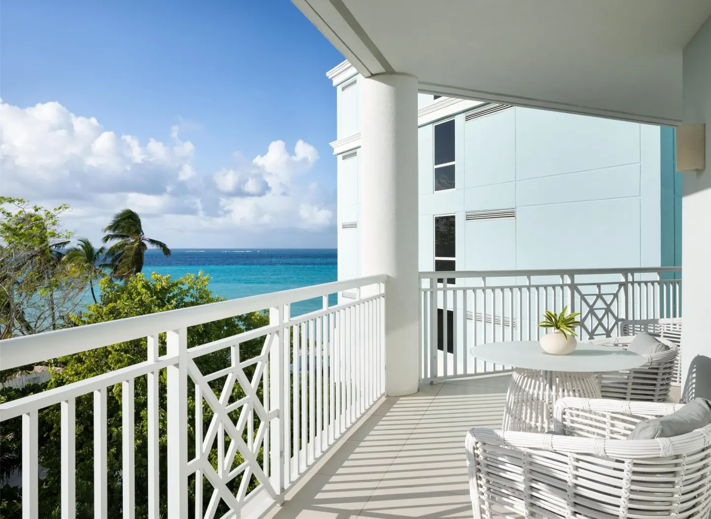 Oceanfront balcony with white seating and turquoise water at Sandals Royal Bahamian.