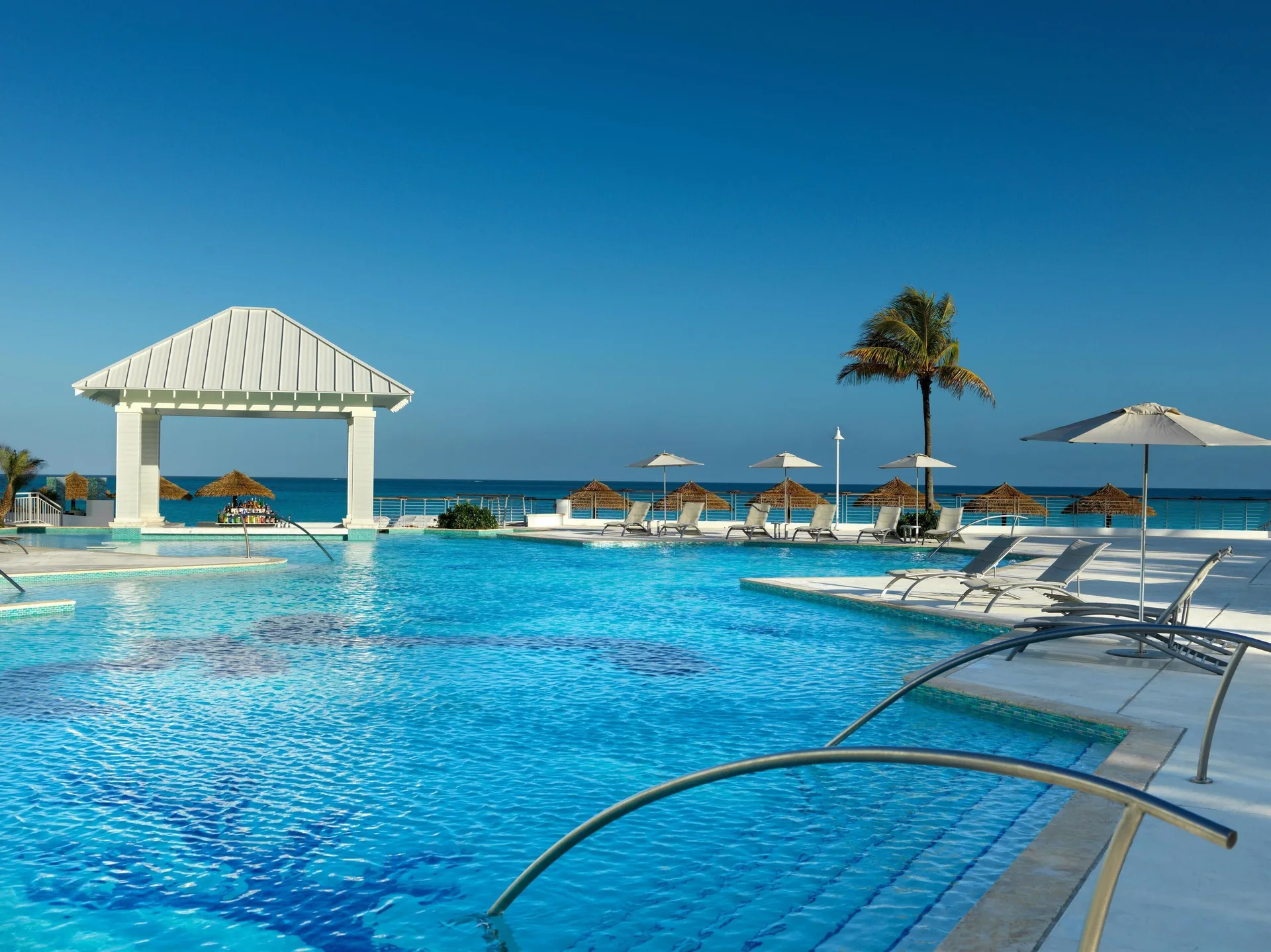Oceanfront pool with loungers and a white pavilion at Sandals Royal Bahamian.