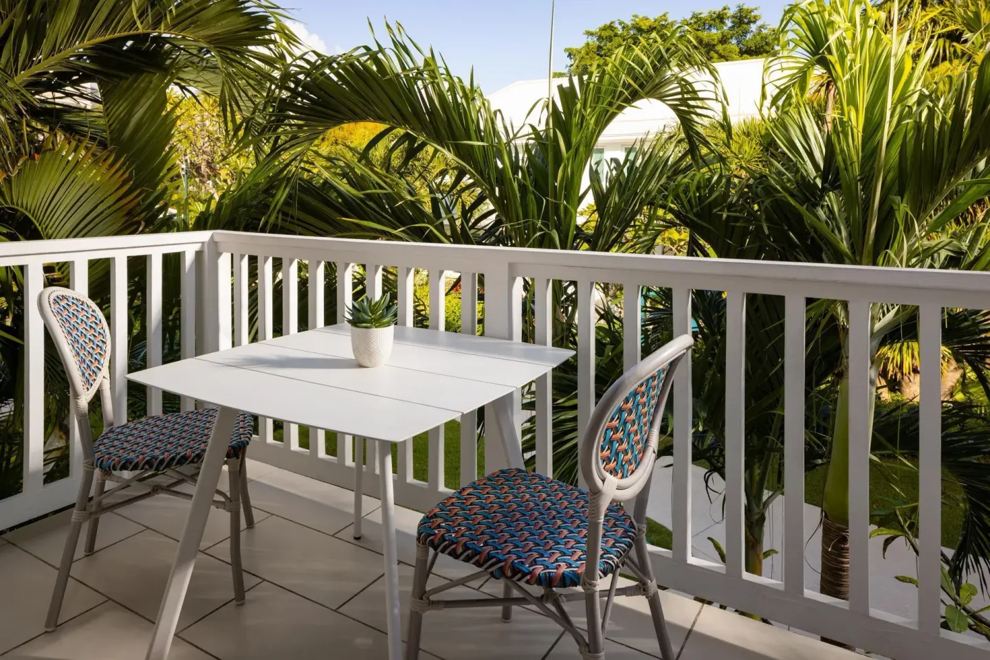 Private balcony with table, chairs, and palms at Sandals Royal Bahamian.