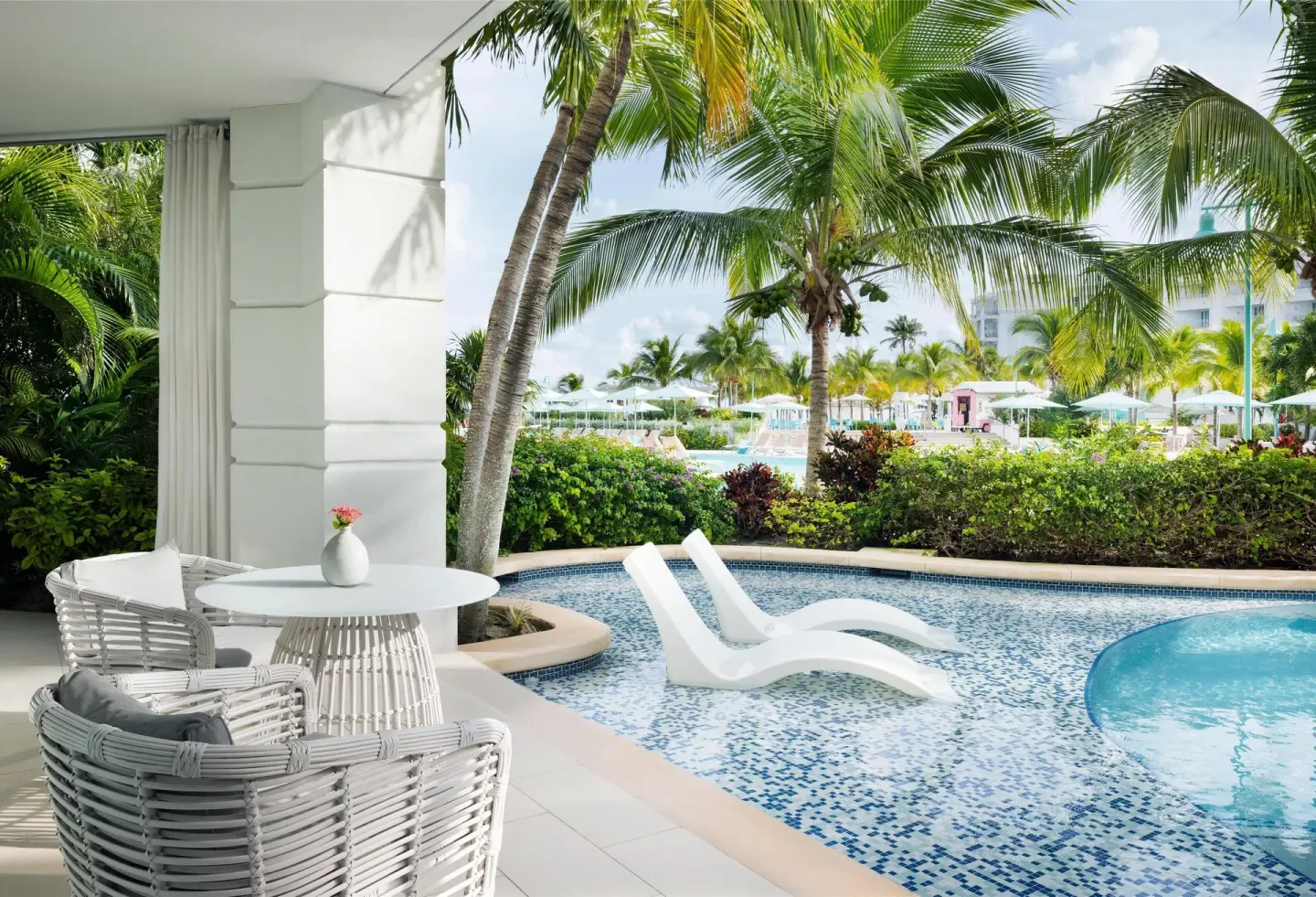 Swim-up patio with plunge pool, loungers, and palm trees at Sandals Royal Bahamian.