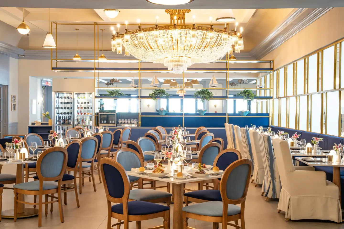 A bright chandelier dining room with blue chairs at Sandals Royal Bahamian.