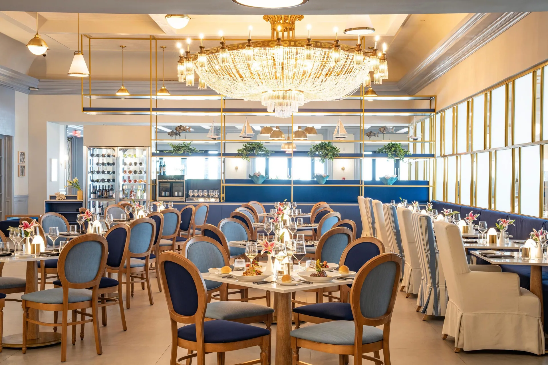 A bright chandelier dining room with blue chairs at Sandals Royal Bahamian.