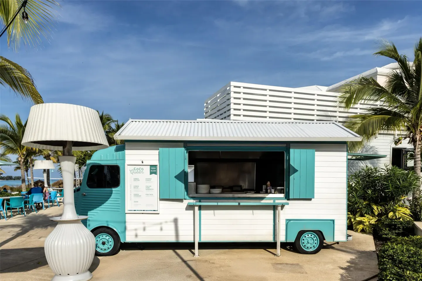 Turquoise Coco Queen food truck at Sandals Royal Bahamian near palms and outdoor seating.
