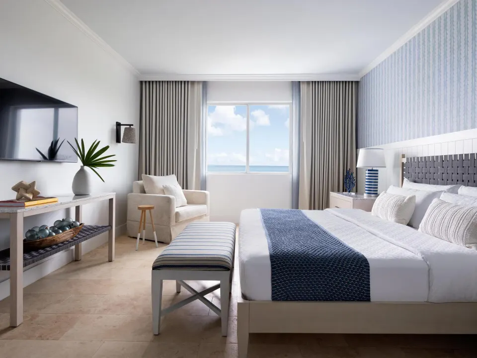 East Bay Oceanview Premium guest room with king bed and ocean-facing window at Sandals Royal Bahamian.