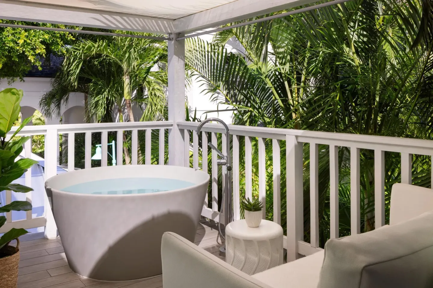 Outdoor soaking tub on a leafy villa balcony at Sandals Royal Bahamian.