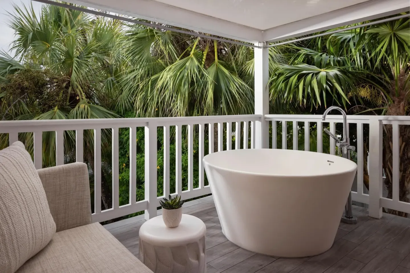 Balcony soaking tub and cushioned seating among palms at Sandals Royal Bahamian.