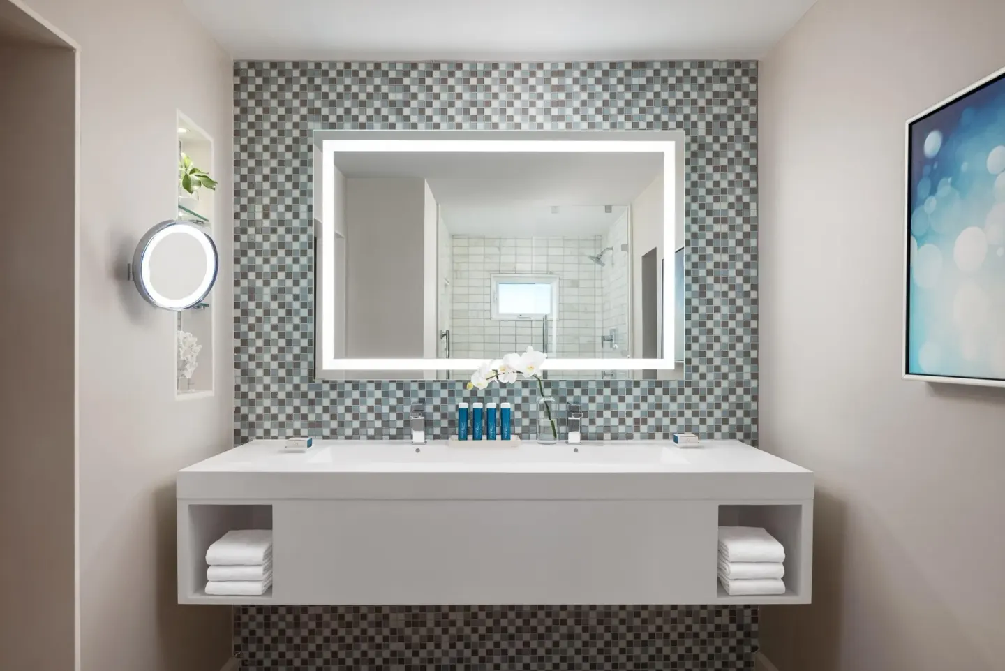 Bathroom vanity with lit mirror and tiled wall in a villa suite at Sandals Royal Bahamian.