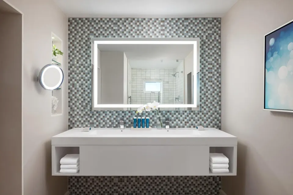 Bathroom vanity with lit mirror and tiled wall in a villa suite at Sandals Royal Bahamian.