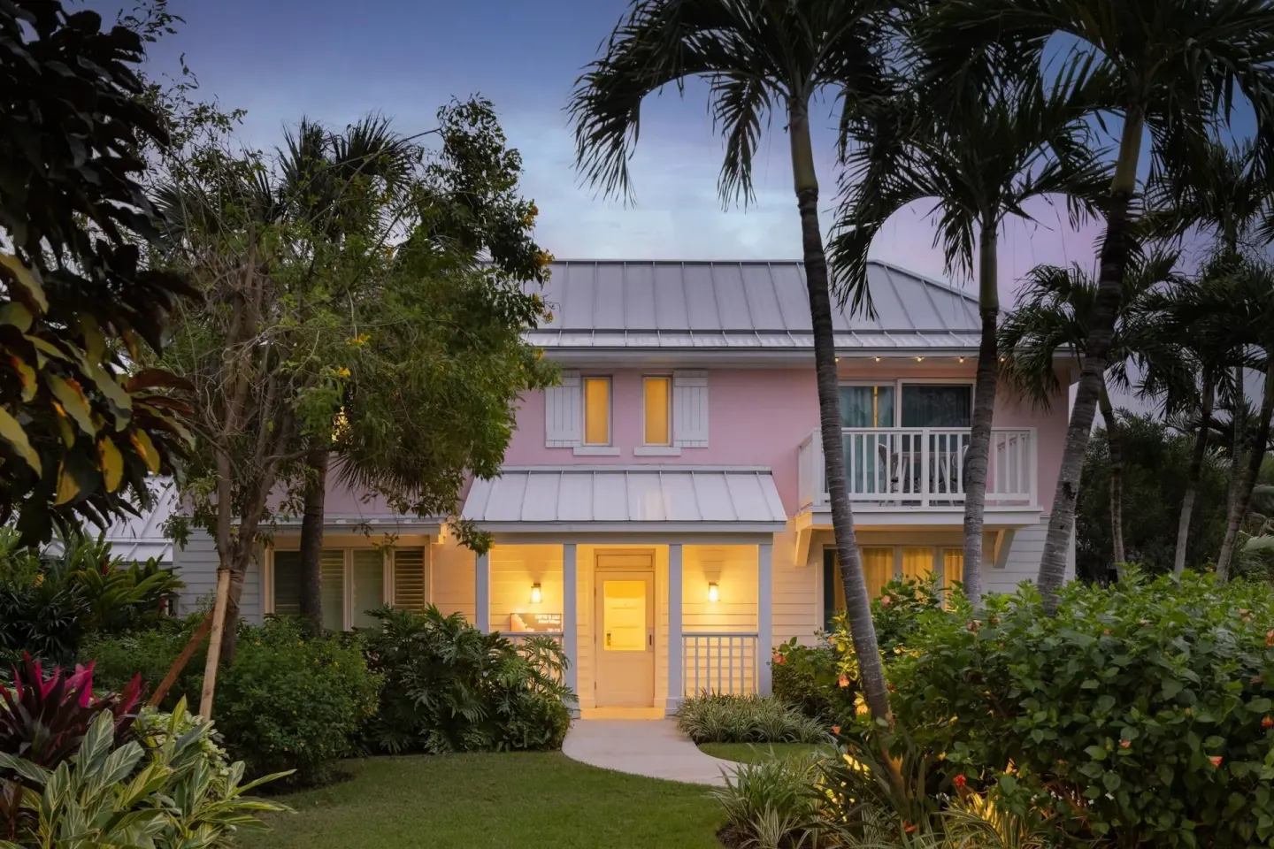 Pink villa exterior at dusk among palms at Sandals Royal Bahamian.