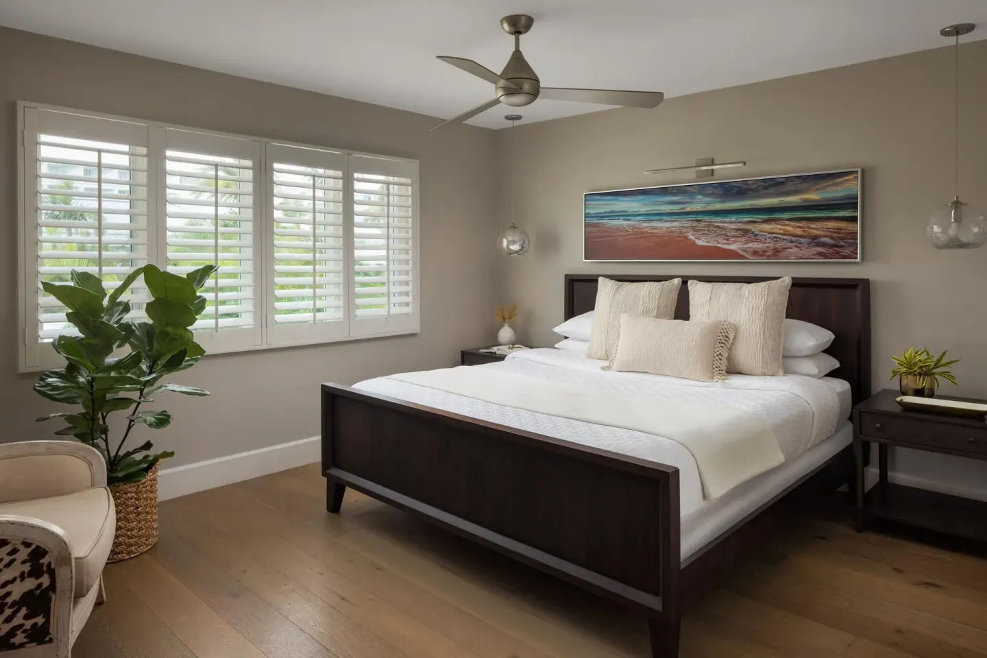 King bedroom with shutters and beach artwork in a villa suite at Sandals Royal Bahamian.