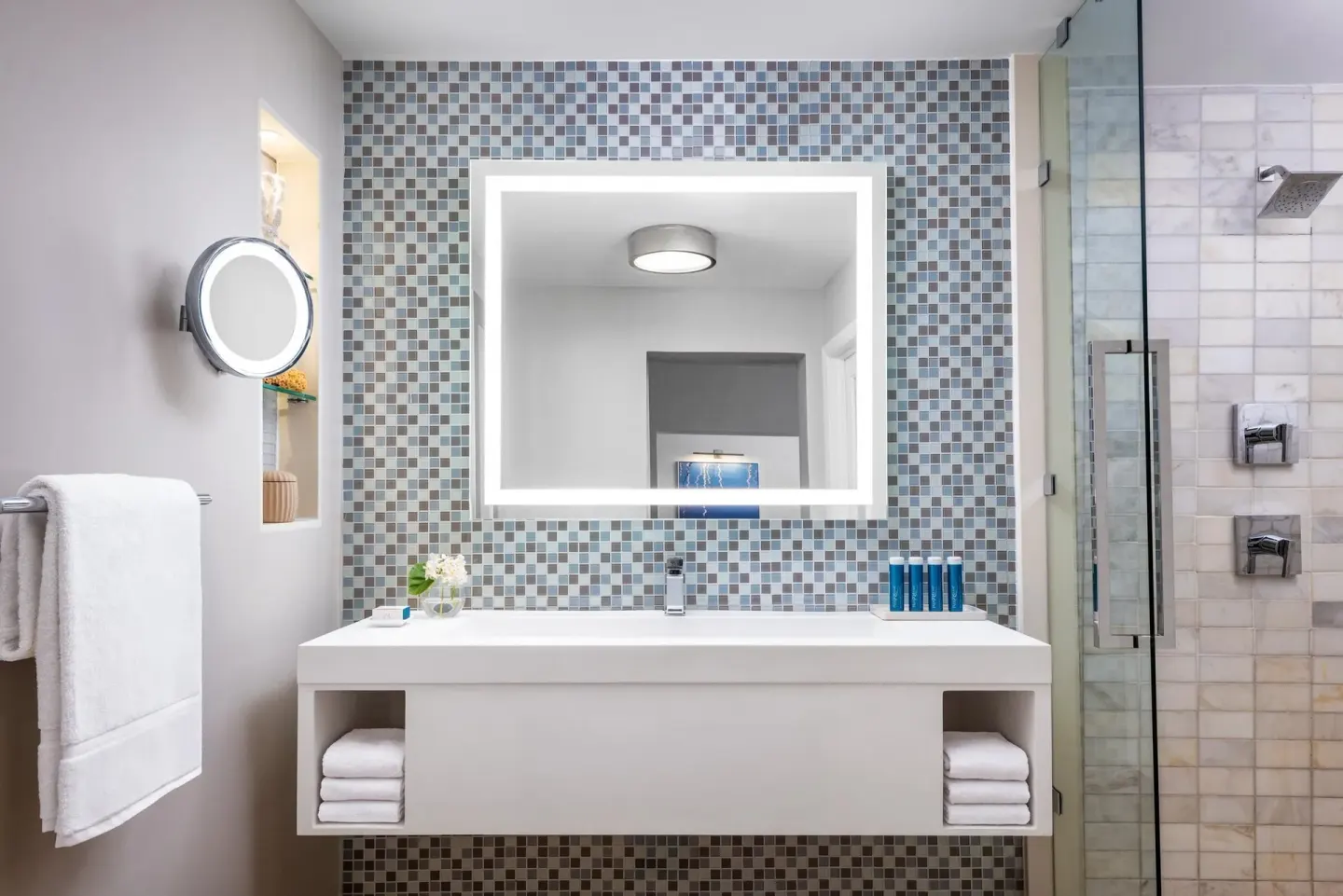 Bathroom vanity and glass shower in a villa suite at Sandals Royal Bahamian with mosaic tile wall.