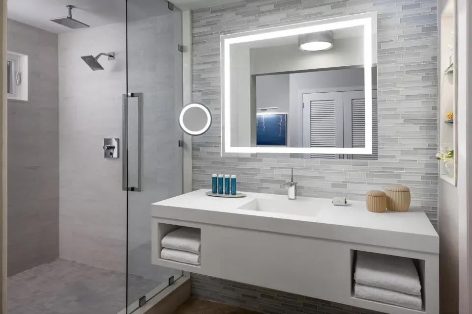 Modern villa bathroom with glass shower and lighted mirror at Sandals Royal Bahamian.
