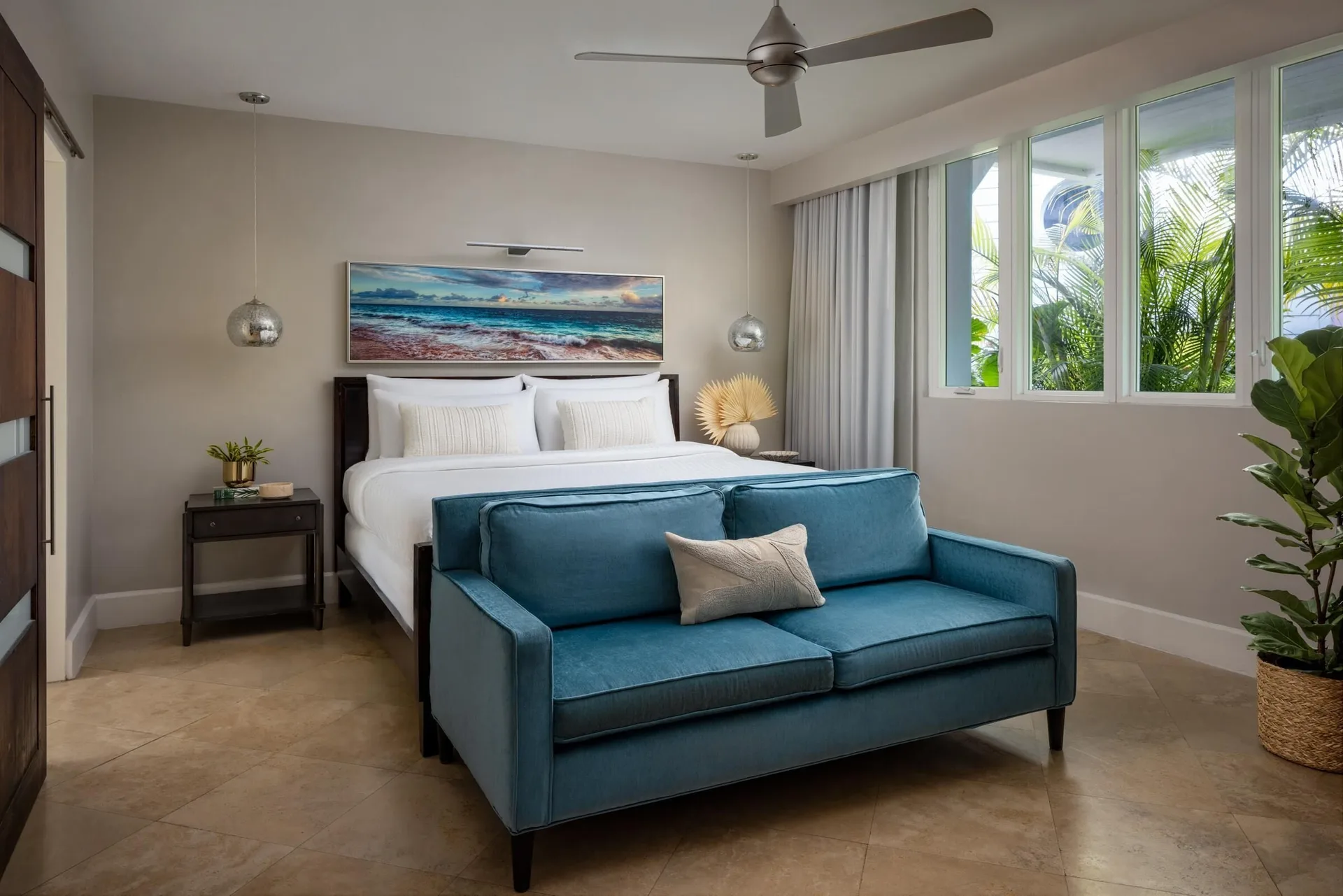 Island Village villa suite bedroom with king bed and blue sofa at Sandals Royal Bahamian.