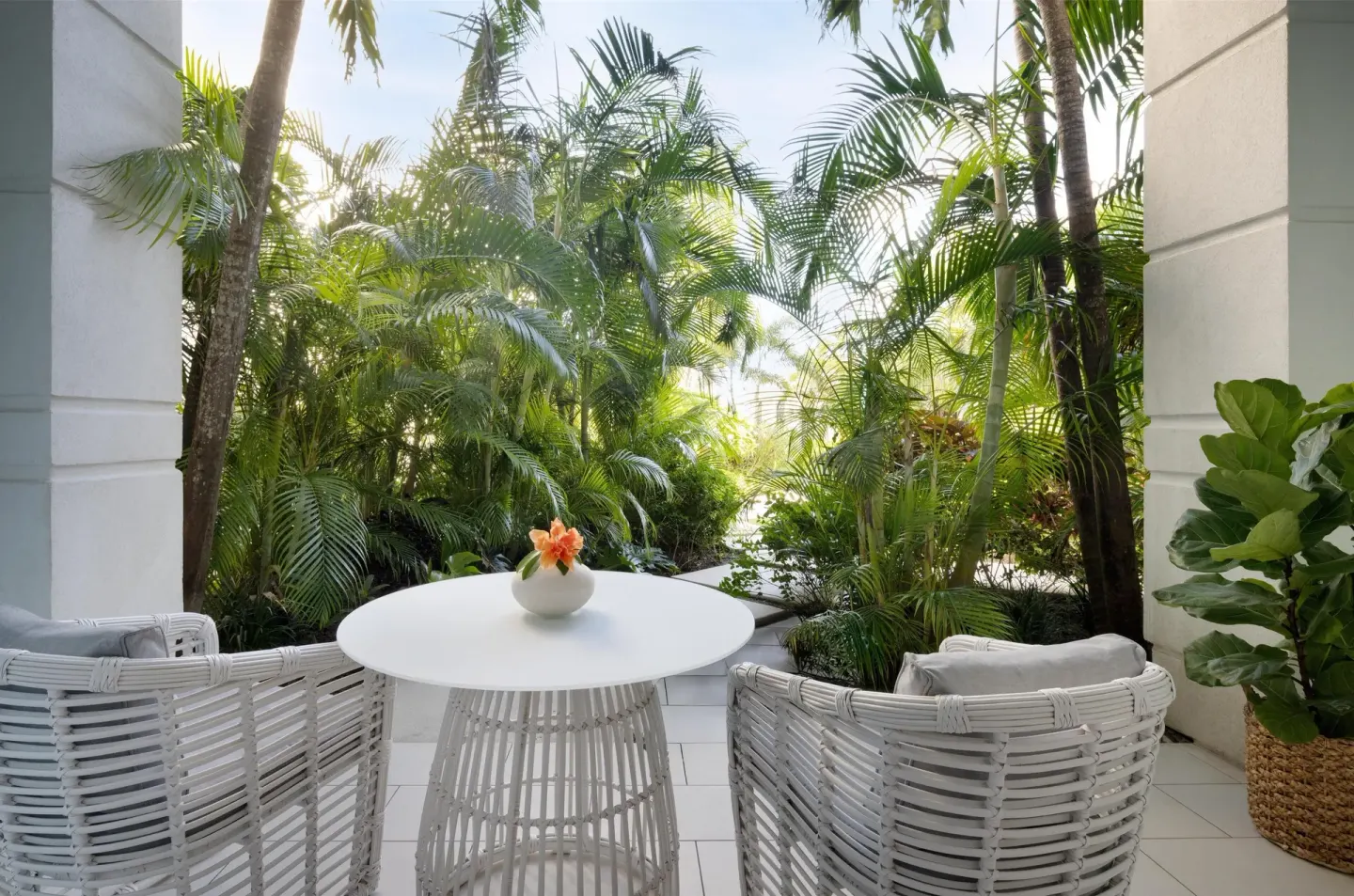 Private walkout patio with white seating and tropical plants at Sandals Royal Bahamian.