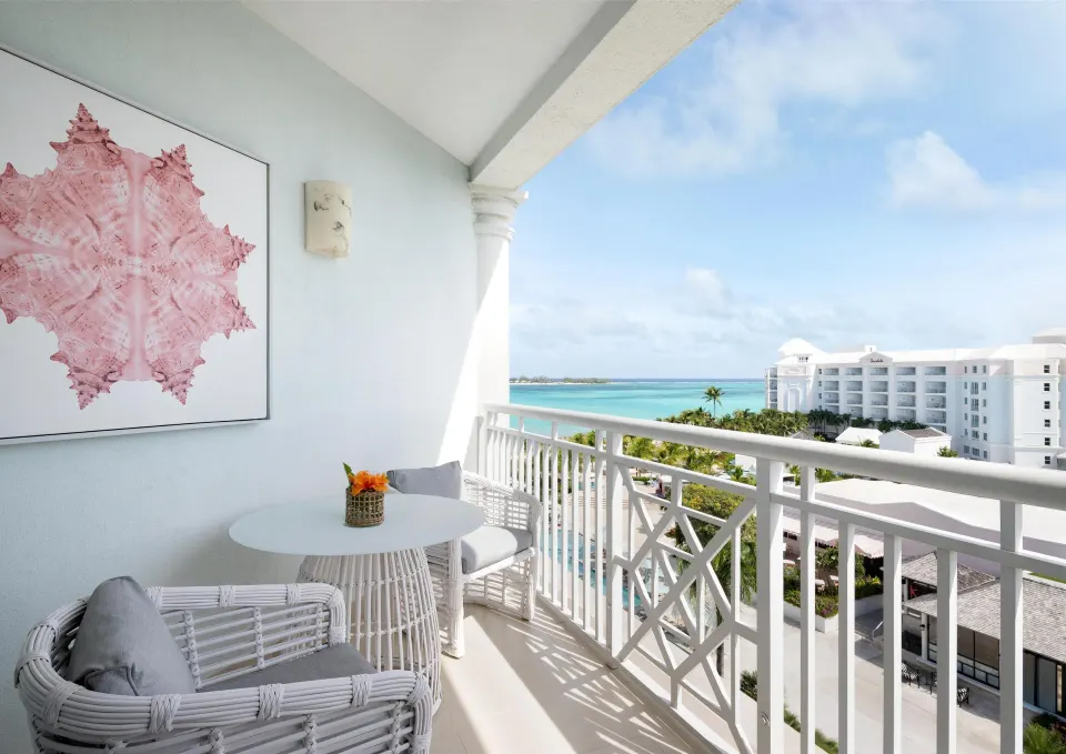 West Bay Honeymoon Oceanview Club Level Suite balcony at Sandals Royal Bahamian with white seating and ocean view.