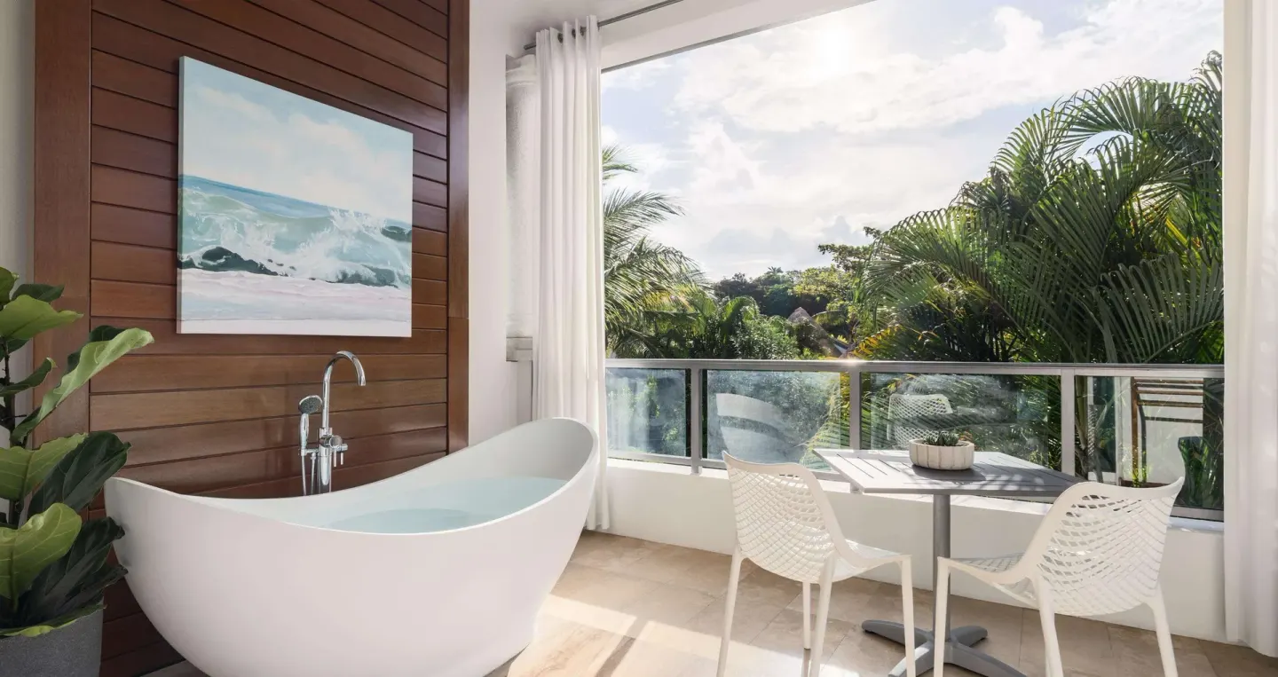 Balcony soaking tub and bistro seating with garden views at Sandals Royal Barbados.