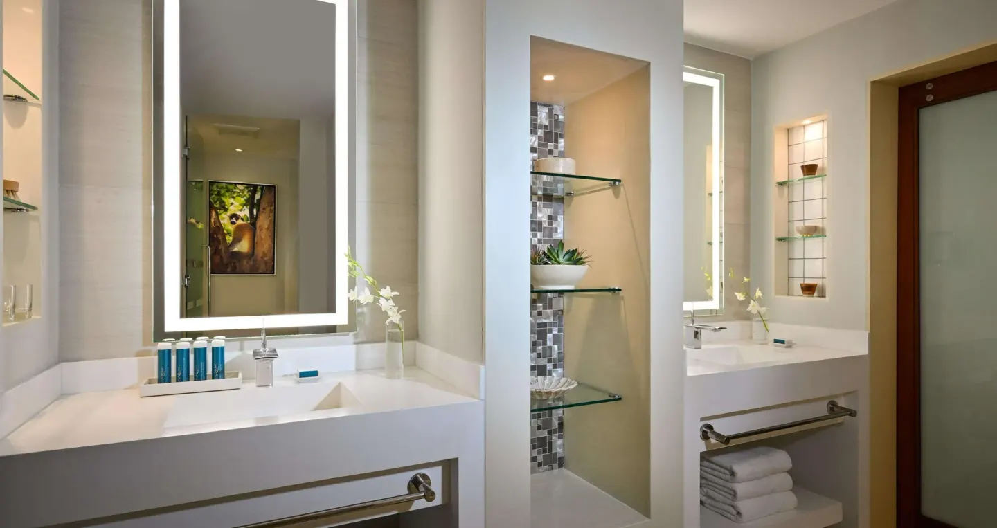 Double vanity bathroom with illuminated mirrors and shelves at Sandals Royal Barbados.