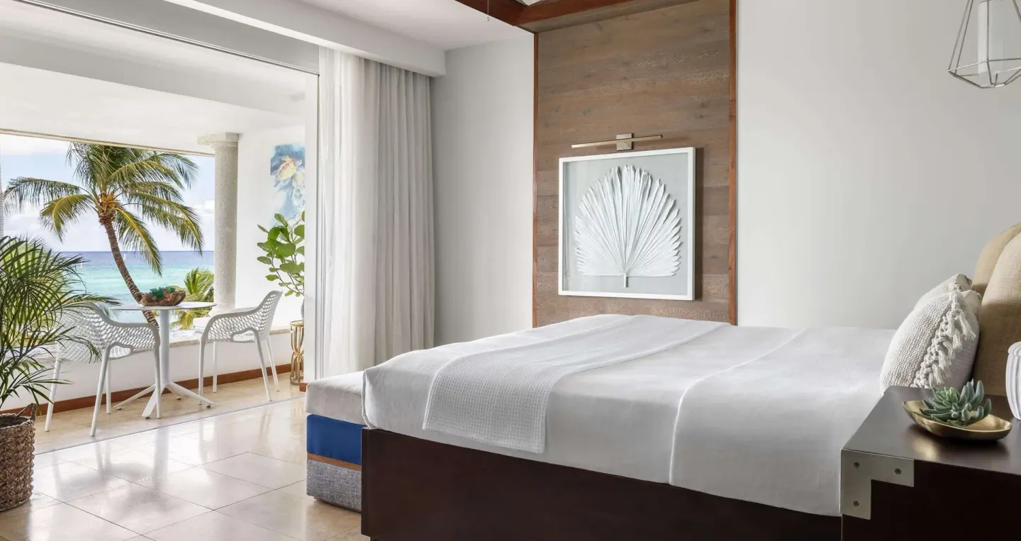 King bed guest room with balcony and ocean view at Sandals Royal Barbados.