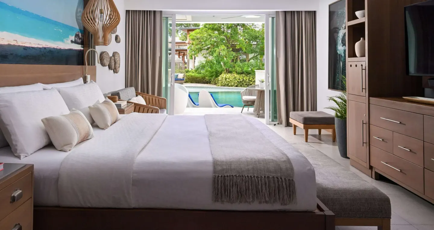 King bed guest room with open doors to a swim-up pool at Sandals Royal Barbados.