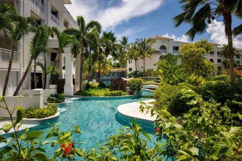 Lagoon pool surrounded by palms and white buildings at Sandals Royal Barbados.