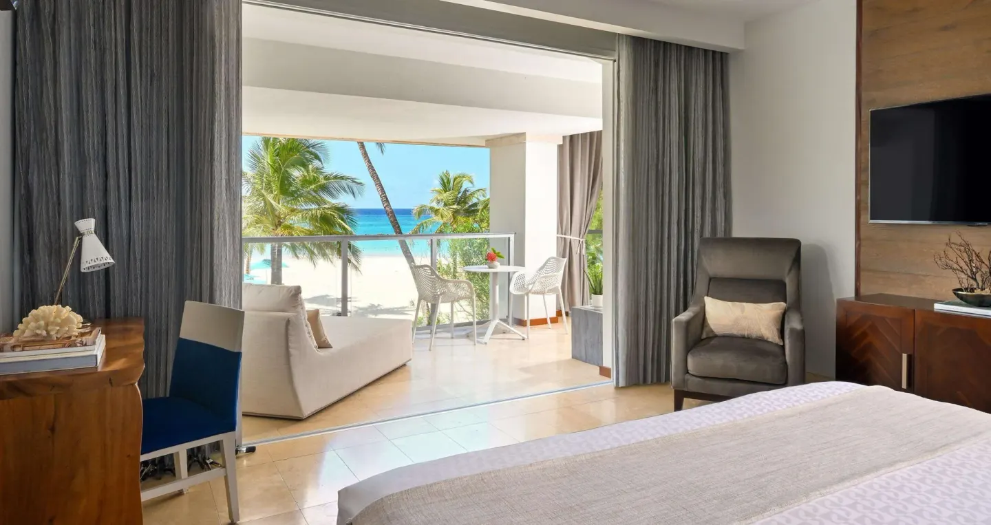 Ocean-view king bed guest room with balcony seating at Sandals Royal Barbados.