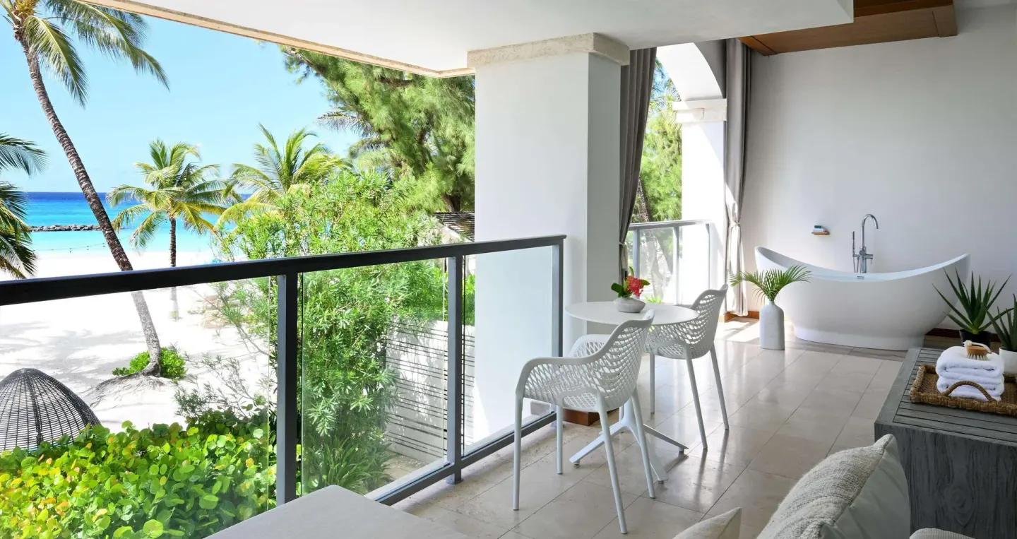 Oceanfront balcony with soaking tub, chairs, and beach view at Sandals Royal Barbados.