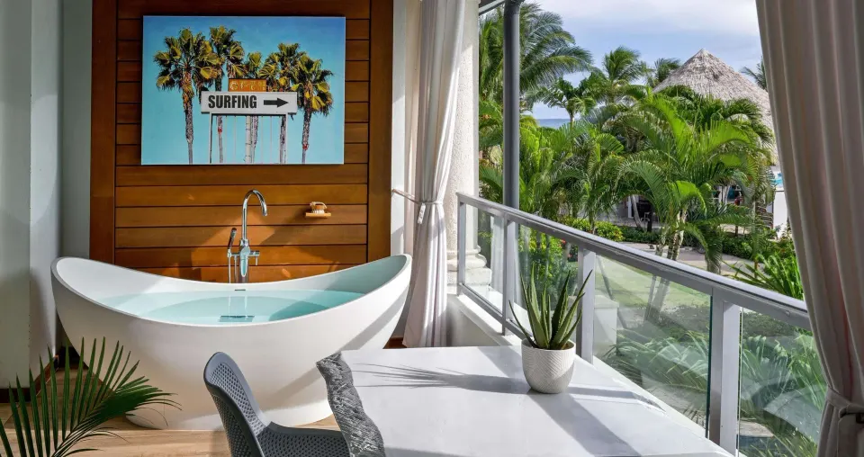 Balcony soaking tub in a one-bedroom suite at Sandals Royal Barbados overlooking tropical gardens.