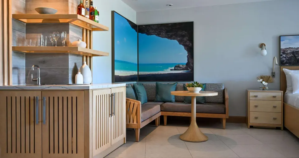 Wet bar and sitting area beside a king bed in a suite at Sandals Royal Barbados.