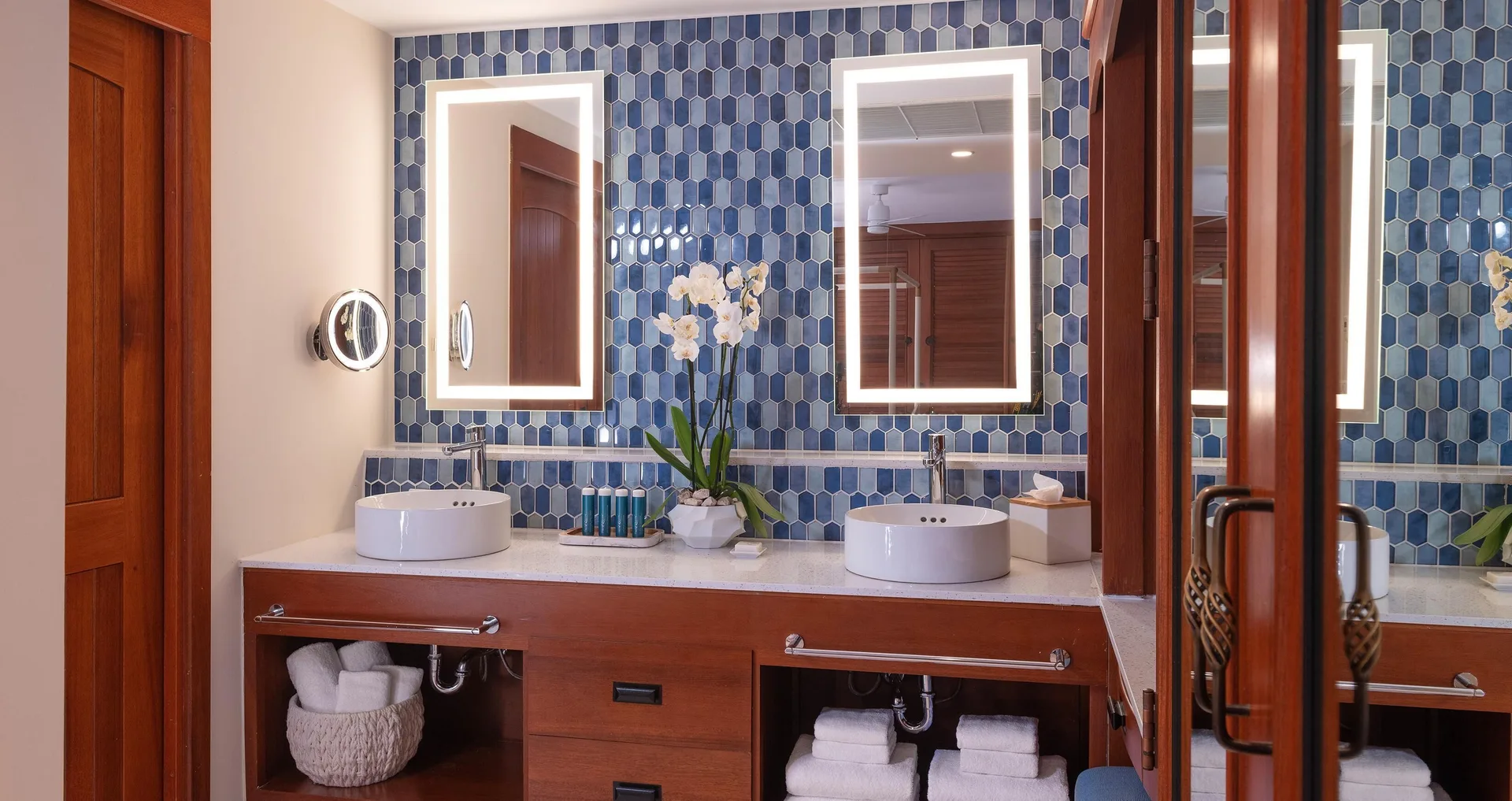 Double vanity bathroom with blue tile and lighted mirrors at Sandals Royal Curacao.