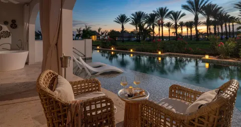 Evening swim-up terrace with wicker chairs and canal pool at Sandals Royal Curacao.
