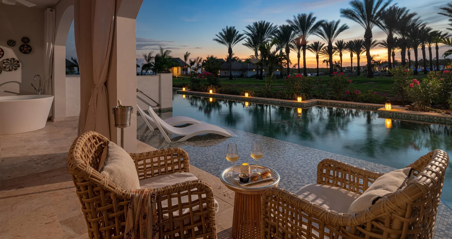 Evening swim-up terrace with wicker chairs and canal pool at Sandals Royal Curacao.