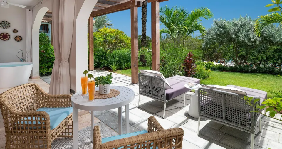 Garden patio with lounge chairs and outdoor tub at Sandals Royal Curacao.