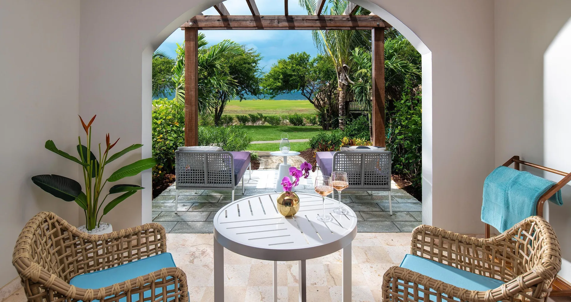 Garden patio seating with ocean glimpse at Sandals Royal Curacao.