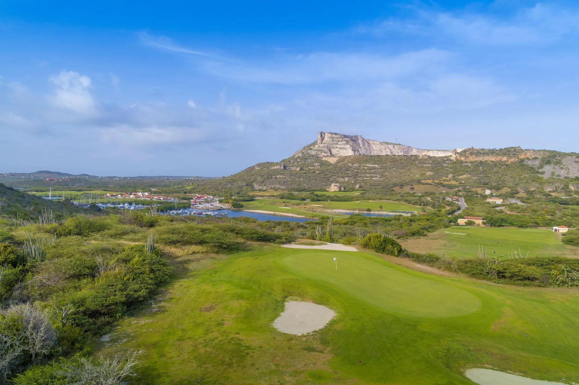 A golf green and rugged hillside landscape near Sandals Royal Curacao.