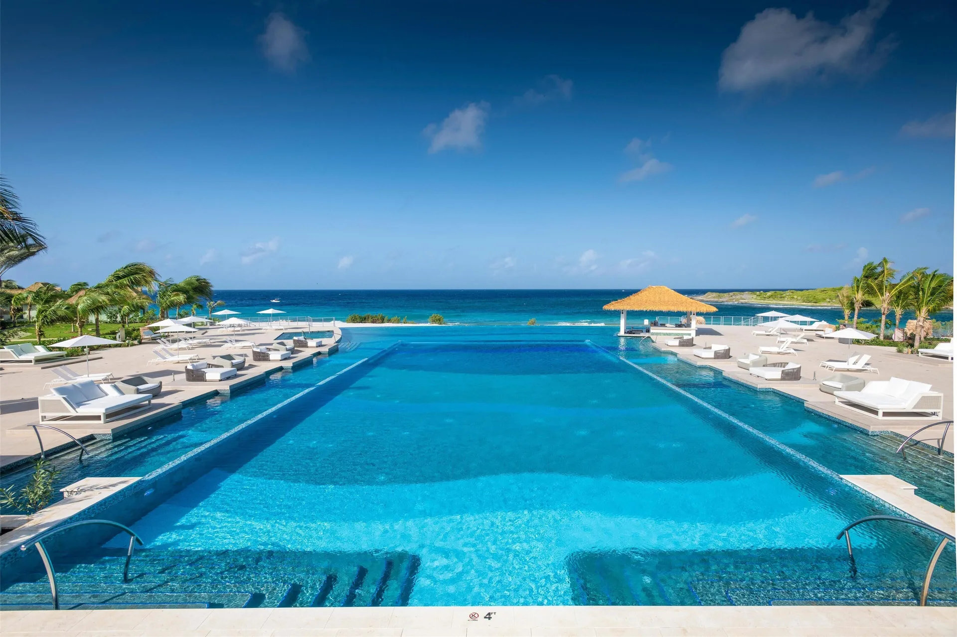 Large ocean-view pool with white loungers at Sandals Royal Curacao.