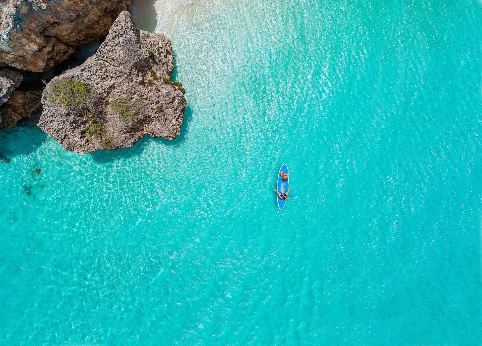 Paddleboarders on clear turquoise water near Sandals Royal Curacao.