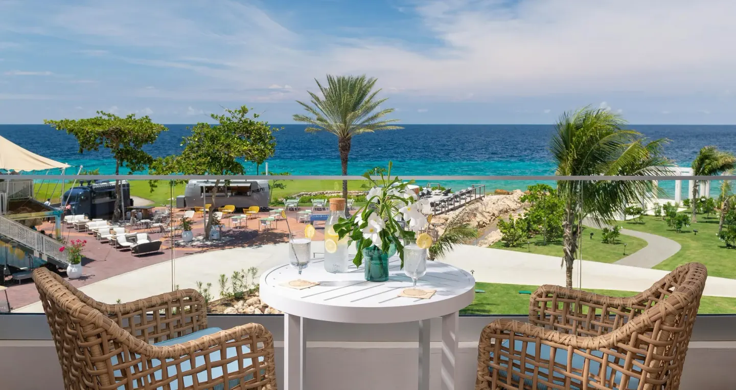 Balcony table with wicker chairs overlooking the sea at Sandals Royal Curacao.