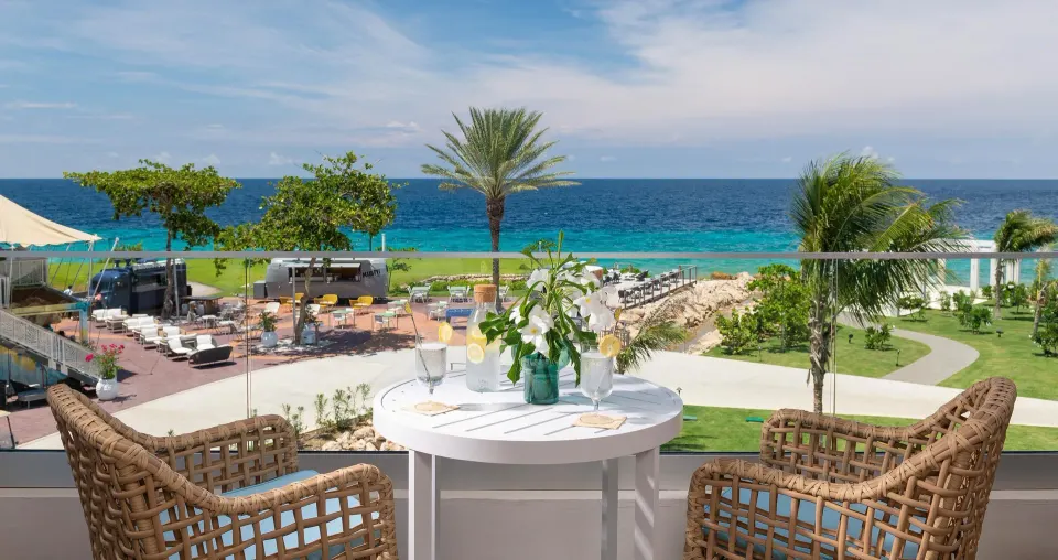 Balcony table with wicker chairs overlooking the sea at Sandals Royal Curacao.