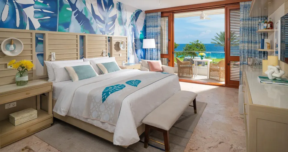 King bed guest room with a sea-facing balcony at Sandals Royal Curacao.