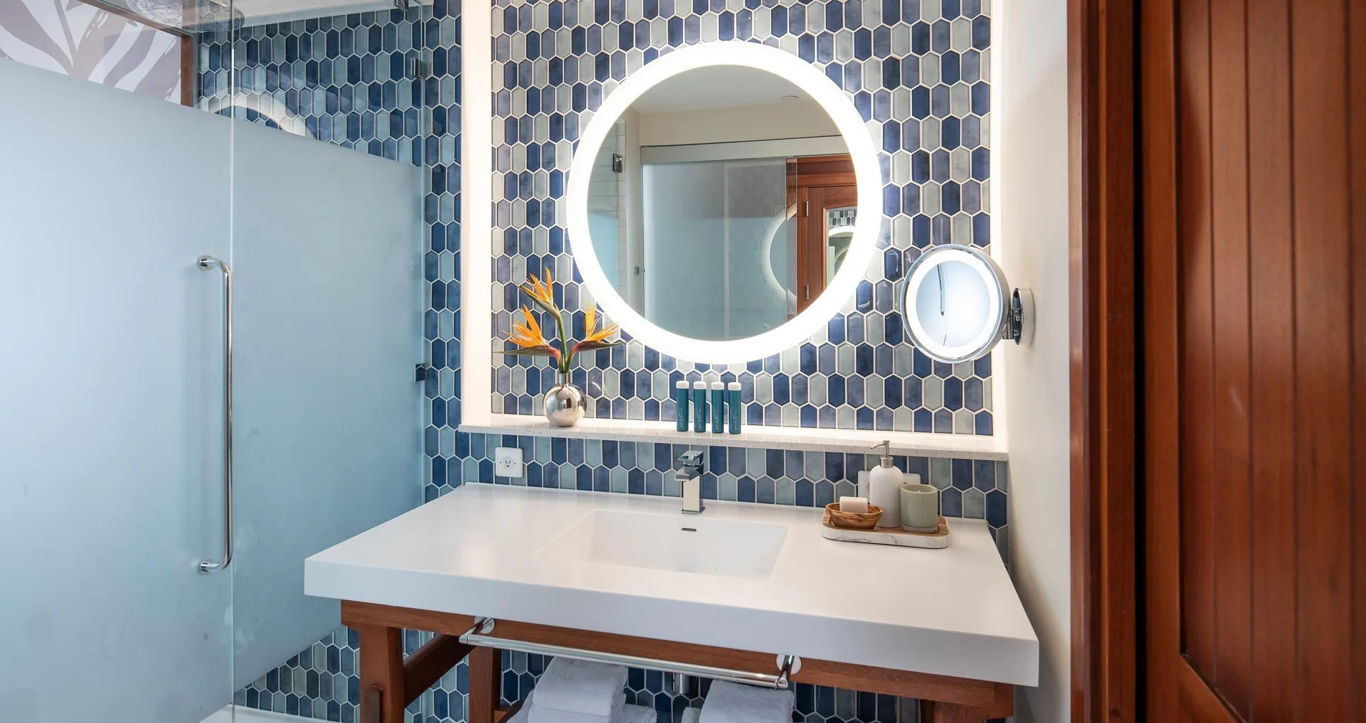 Single vanity bathroom with round lighted mirror at Sandals Royal Curacao.