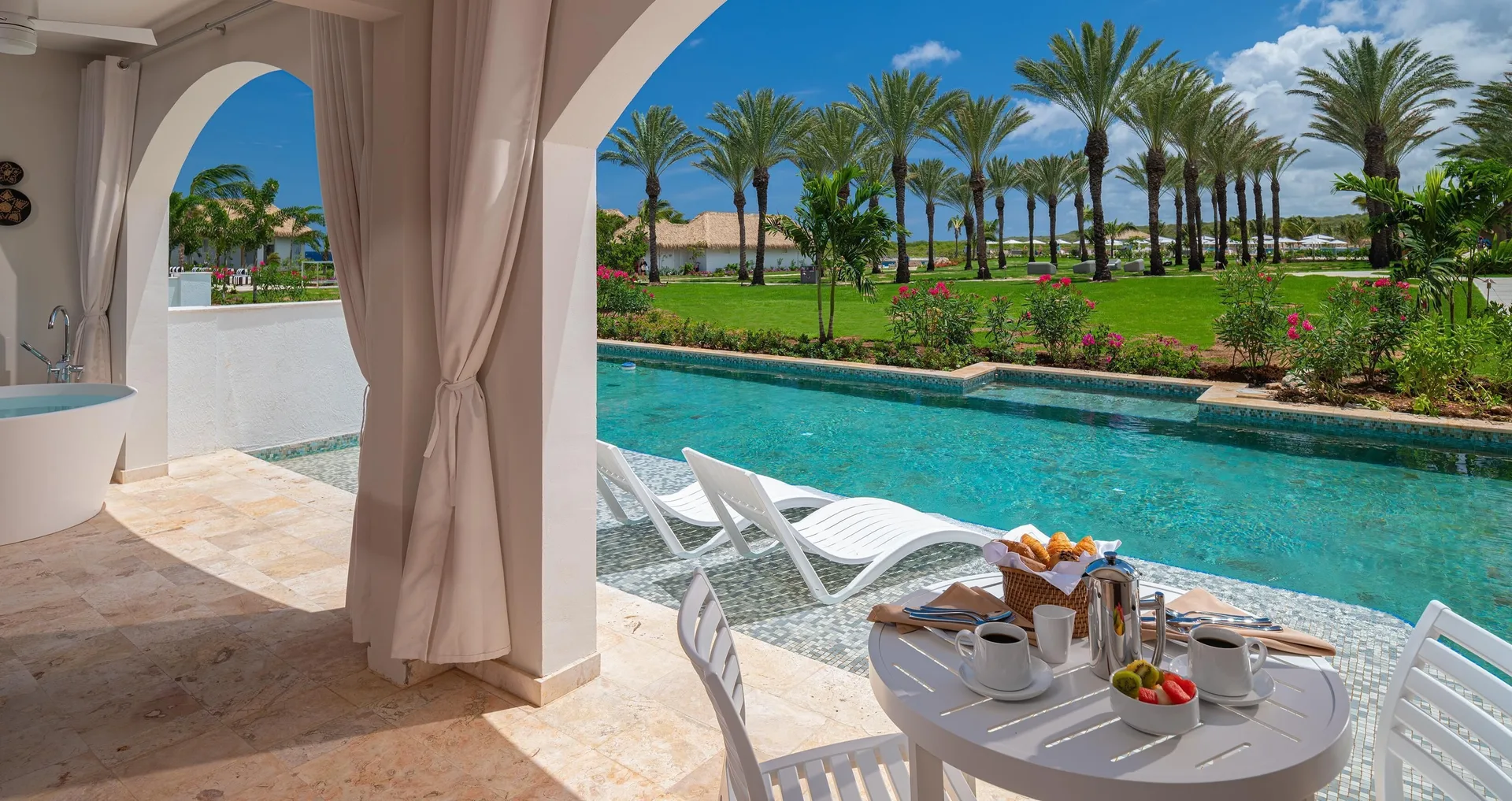 Swim-up patio with breakfast table and lounge chairs at Sandals Royal Curacao.